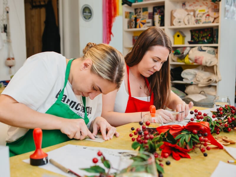 Two women making prints in a Christmas printmaking class